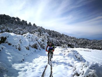 Man skiing on snowcapped mountain against sky