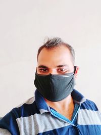 Portrait of young man covering face against white background