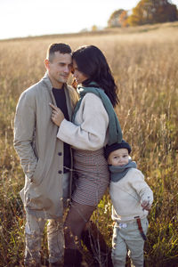 Stylish family with a boy child on a field in the dry grass in autumn