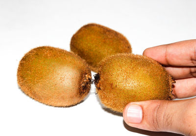 Close-up of hand holding fruit over white background