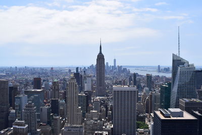 Aerial view of buildings in city against cloudy sky