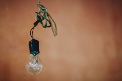 Close-up of light bulb hanging on wall