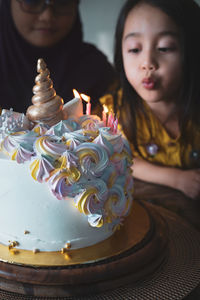 Close-up of girl blowing birthday candles with sister in party