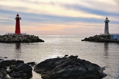 Lighthouse by sea against sky during sunset