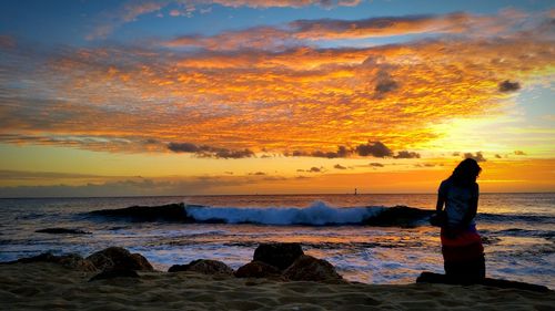 People standing on rock at sunset