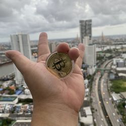 Close-up of hand holding cityscape against sky