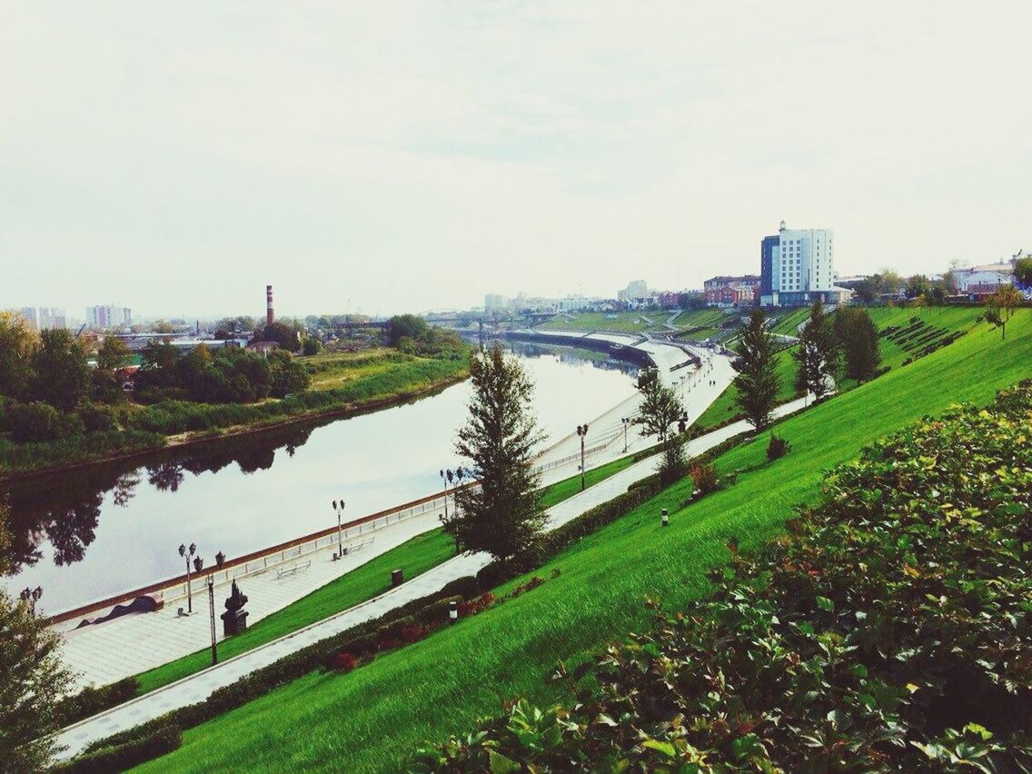 architecture, built structure, grass, water, building exterior, river, sky, city, connection, bridge - man made structure, tree, men, lifestyles, leisure activity, day, growth, person, green color, incidental people