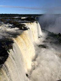 Scenic view of waterfall in sea against sky