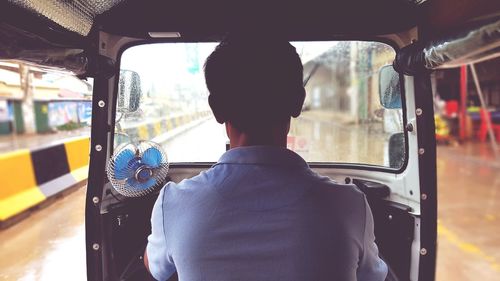 Rear view of man driving jinrikisha on street