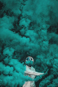 Man wearing helmet holding distress flare while standing amidst smoke
