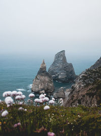 Scenic view of rocks by sea against sky