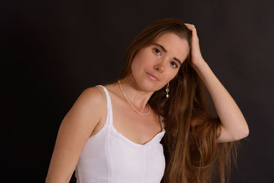 Portrait of young woman against black background