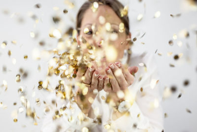 Woman blowing confetti against white background