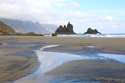 Scenic view of beach and mountains against sky