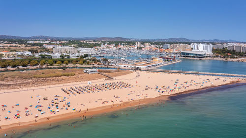 High angle view of city by sea against clear blue sky