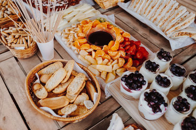 Sandwiches, donuts, yogurt, fruits banana, kiwi, blueberries, strawberries on a wooden table