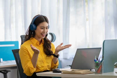 Cheerful businesswoman gesturing while talking on video call at office