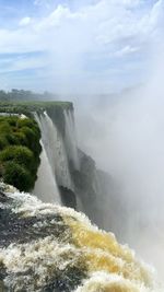 Scenic view of waterfall against sky