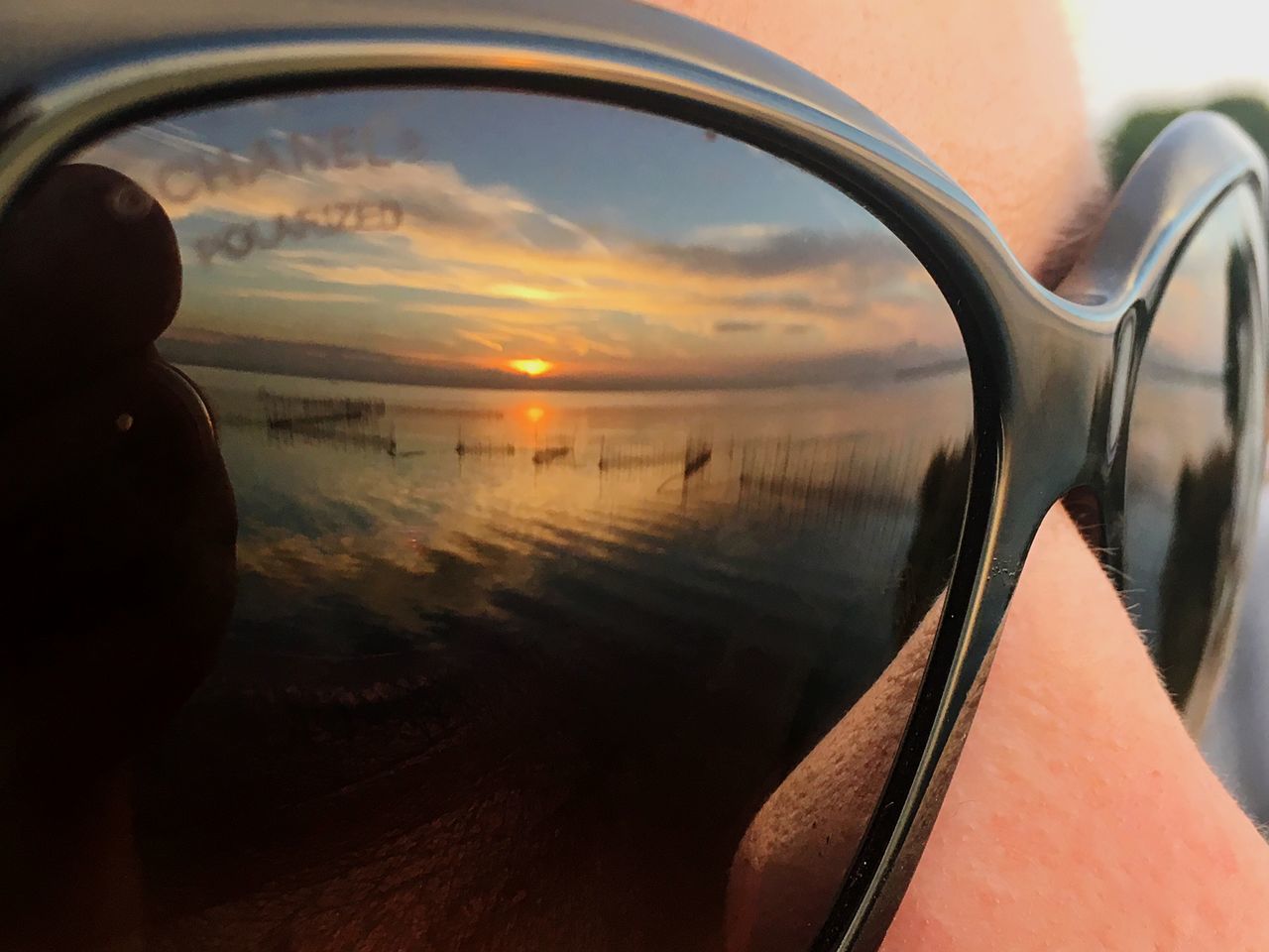 REFLECTION OF MAN IN SUNGLASSES ON BEACH DURING SUNSET
