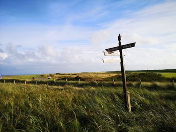 Cross on field against sky