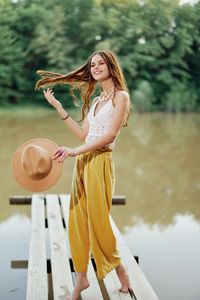 Young woman with arms raised standing against trees