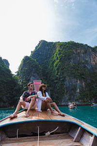 Rear view of woman sitting on boat against mountain