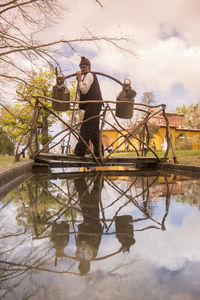 Reflection of man standing on water in lake against sky