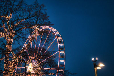 Low angle view of illuminated ferris wheel against sky at night at christmas market