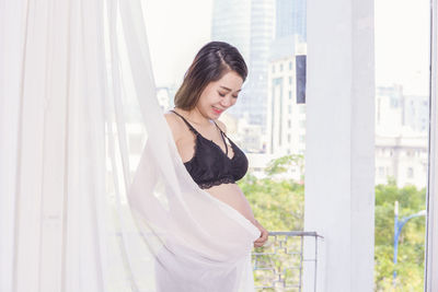 Side view of young woman standing against railing