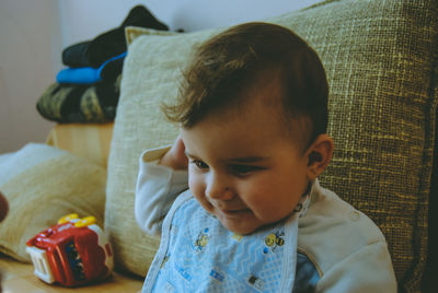 Close-up of cute boy sitting on bed at home