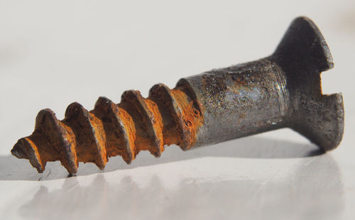 Close-up of rusty metal on table against white background