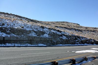 Road by mountains against clear blue sky