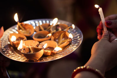 Cropped image of women holding lit candle