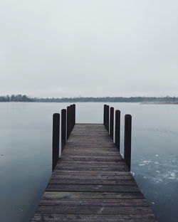 Wooden pier on lake against sky