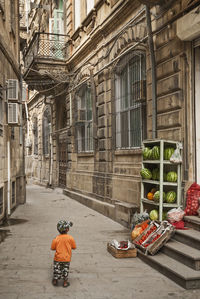 Rear view of boy on street against building