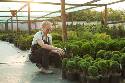 Young woman sitting on potted plant