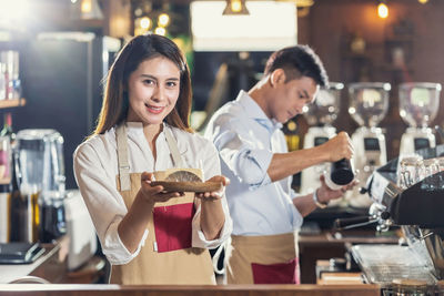 Portrait of a smiling young woman standing at cafe