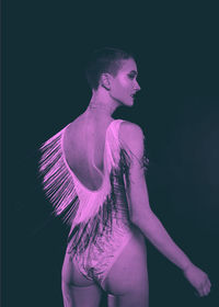 Side view of woman standing against black background