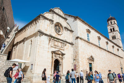 Group of people outside historic building against sky