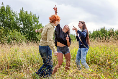 Group of three friends boy and two girls running and having fun together outdoors