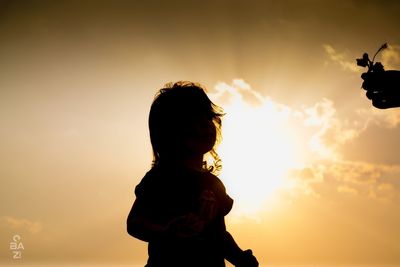 Silhouette woman standing against sky during sunset