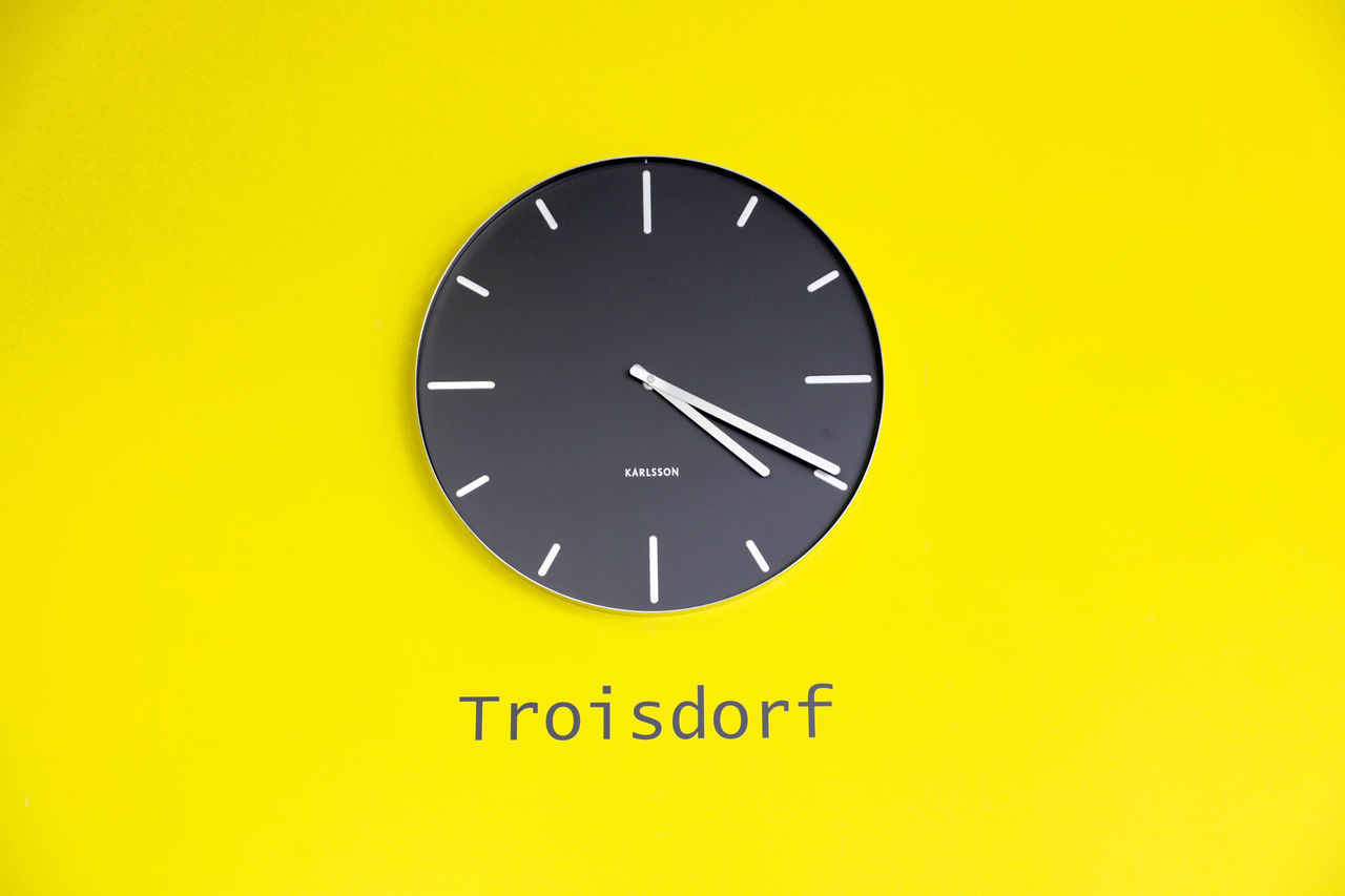 CLOSE-UP OF YELLOW CLOCK ON WALL