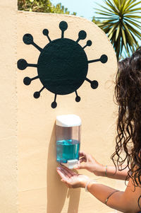 Cropped hand of woman using hand sanitizer outdoors