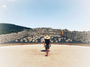 Woman standing by wall against clear sky