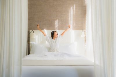 Midsection of woman sitting on bed