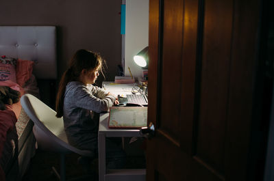 Side view of young woman sitting at home