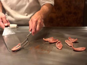 Midsection of man preparing meat on stove in kitchen