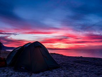 Tent on beach against sky during sunset