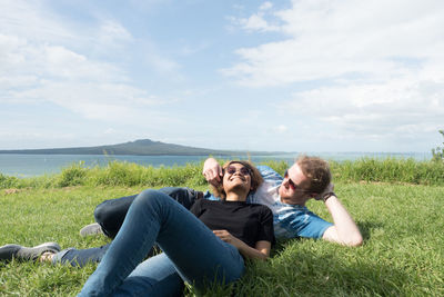 Rear view of couple sitting on land against sky