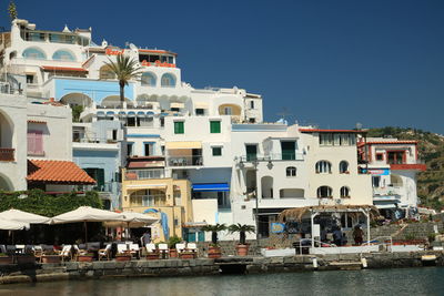 Buildings by sea against clear blue sky